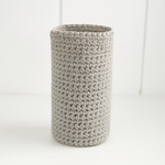 
                    
                      Portabotella cilíndrico de crochet beige texturizado sobre fondo blanco-
                    
                  