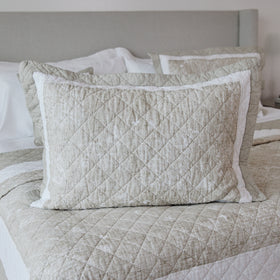 Funda de almohada Preston beige acolchada con borde blanco en cama-