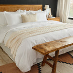 
                    
                      Cama con sábanas blancas, edredón beige y banco de madera-blanco
                    
                  