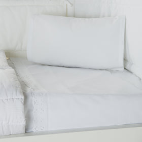 Sábana blanca con broderie en cama impecablemente tendida-blanquecino