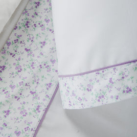 Sábana blanca con pequeñas flores lila y verdes, detalle de esquina-lila