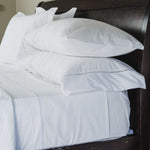 
                    
                      Juego de sábanas blancas de algodón sobre cama con cabecera negra-blanco
                    
                  