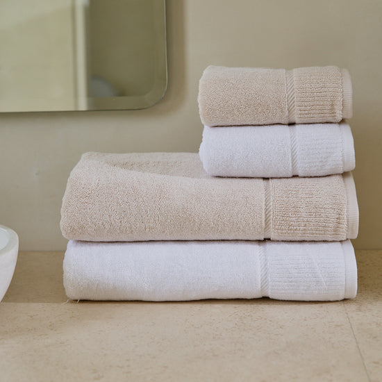 Set de toallas Supreme en tonos beige y blanco apiladas-