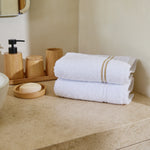 
                    
                      Dos toallas blancas con líneas beige en contador de baño-beige
                    
                  