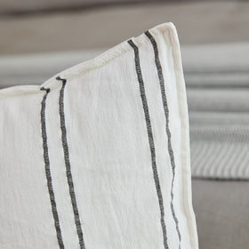 Almohada blanca con rayas grises verticales sobre sofá gris-