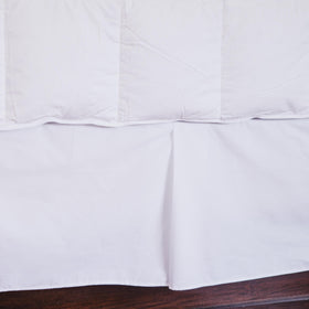 Cubrecama blanco de piqué colgando sobre base de cama de madera-blanco