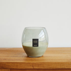 Vela de cera blanca en vaso de vidrio sobre mesa de madera-arrayán