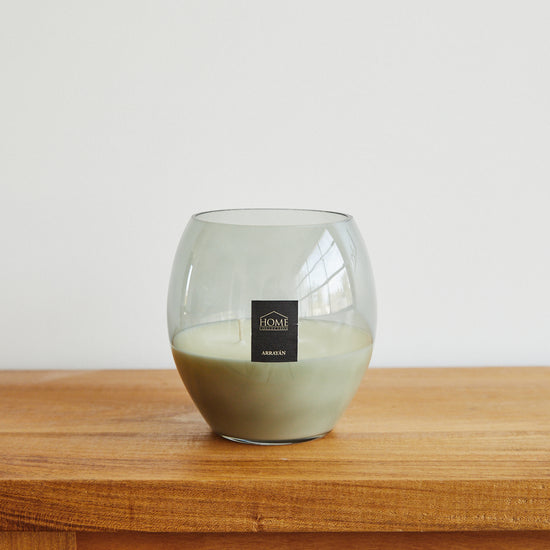 Vela de cera blanca en vaso de vidrio sobre mesa de madera-arrayán
