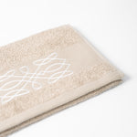 
                    
                      Toalla Viva beige con diseño blanco decorativo sobre fondo neutro-beige
                    
                  